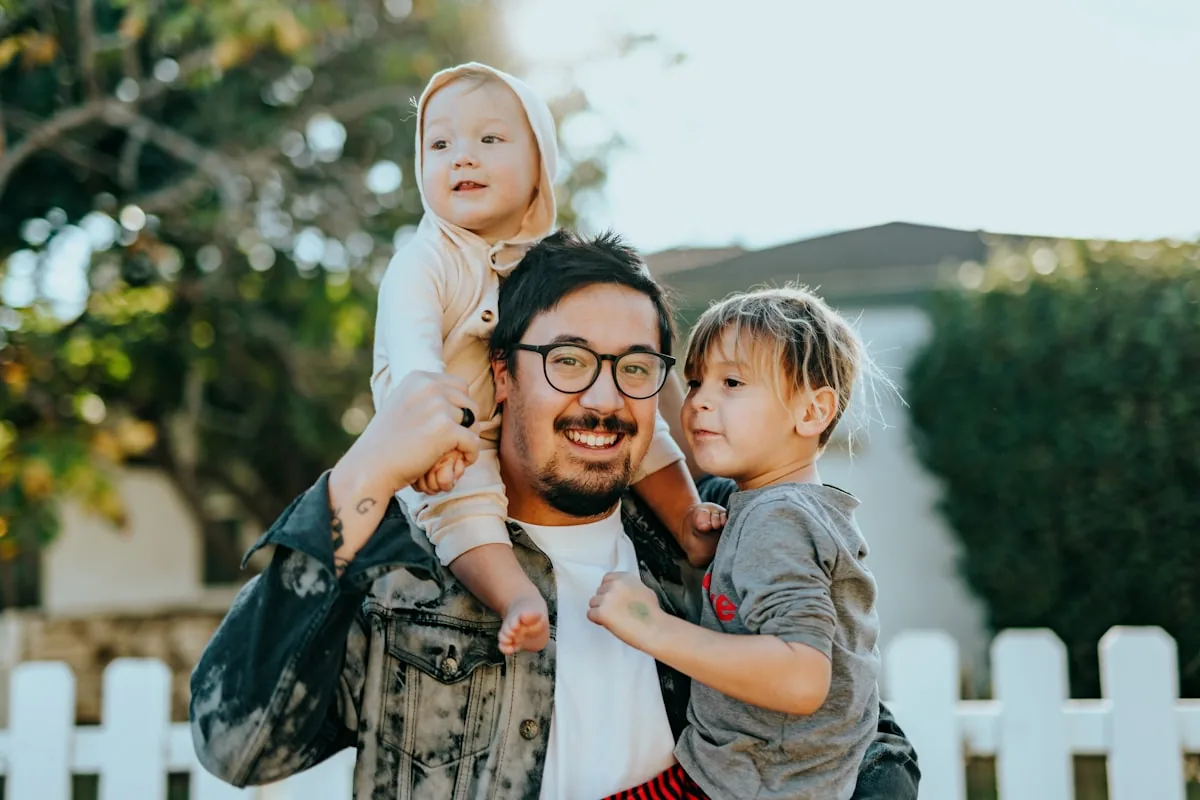 A father carrying his two young children